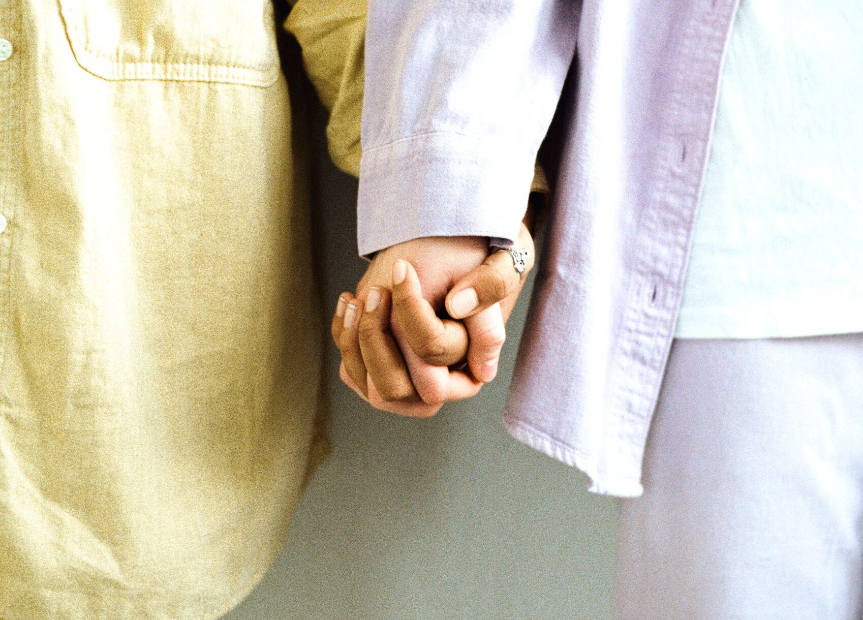 A loving couple holding hands dressed in casual pastel outfits, conveying affection.