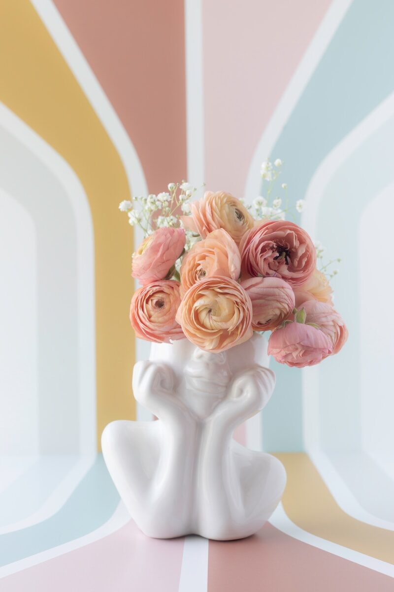 Flowers in a unique vase sit in front of stripes